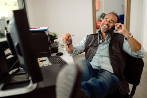 Happy mechanic making a phone call while relaxing in the office - Vinson Technical Solutions